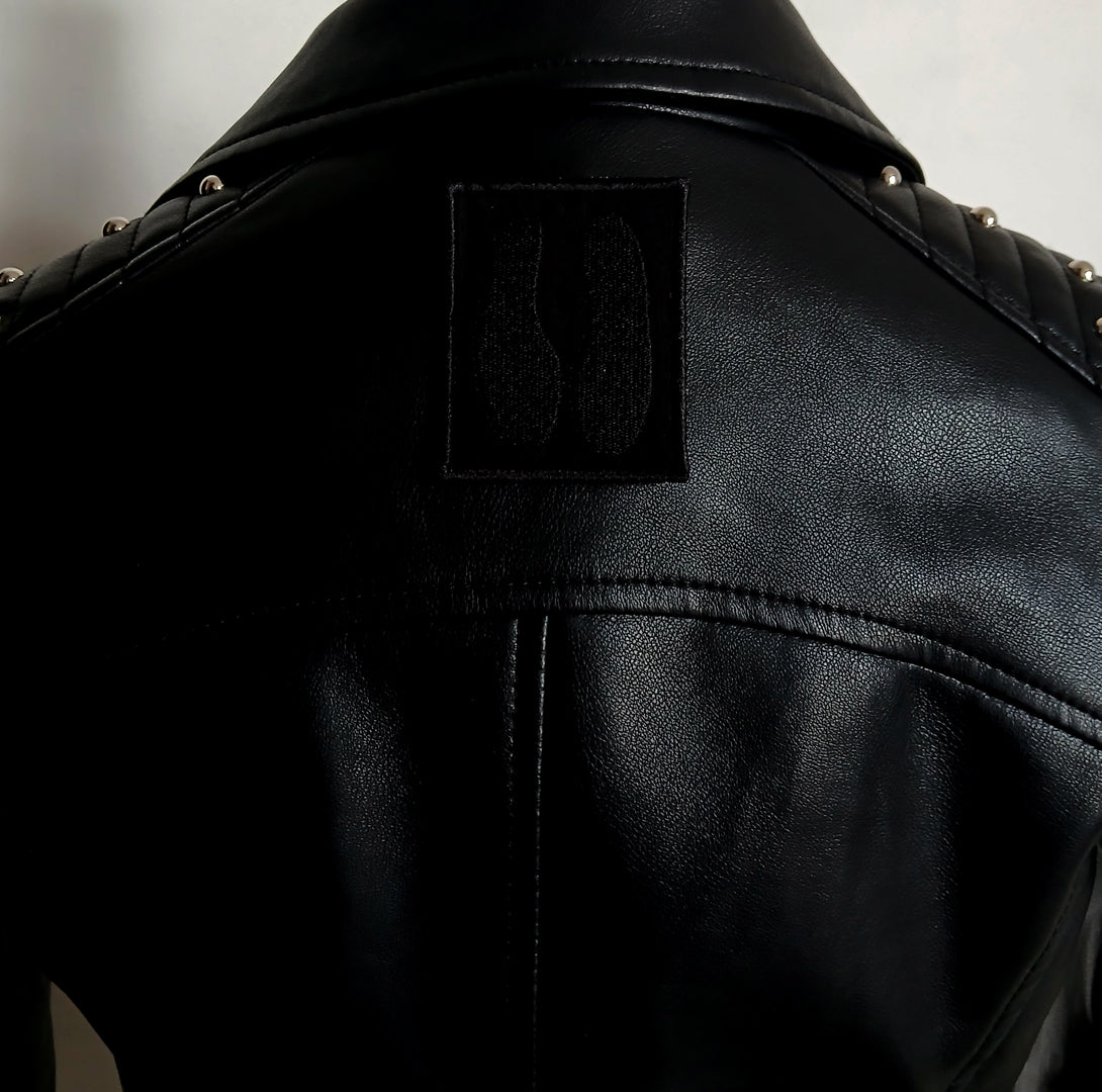 Close-up of a black leather jacket with an embroidered goat hoof patch on the back