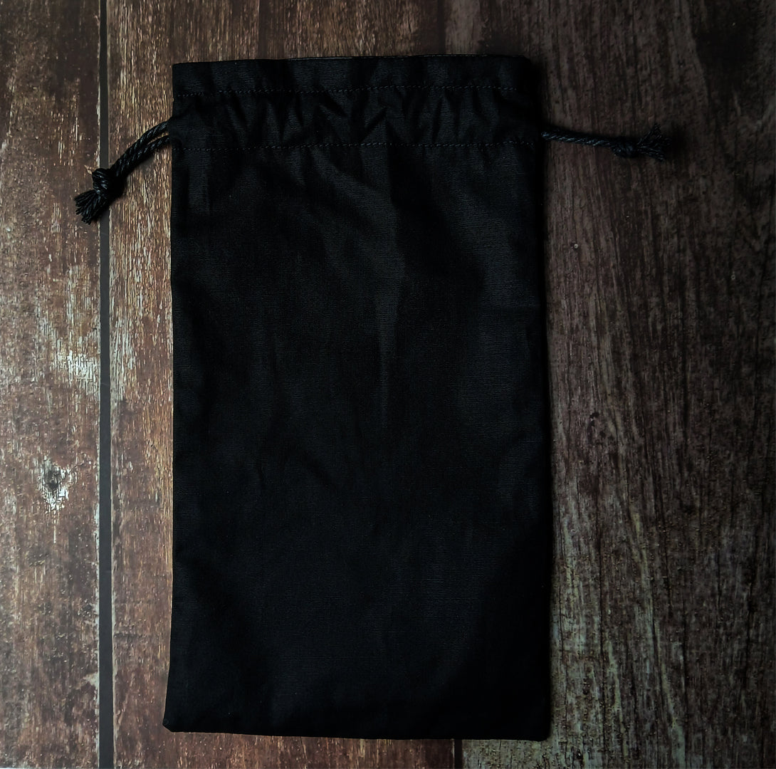 Back of black drawstring pouch on a wooden surface