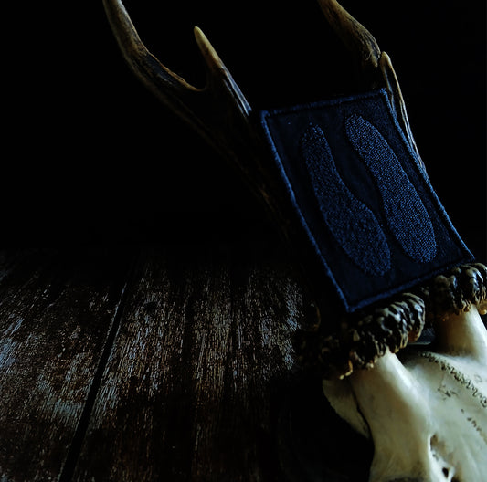 Close-up of black embroidered patch resting deer antlers on a dark background