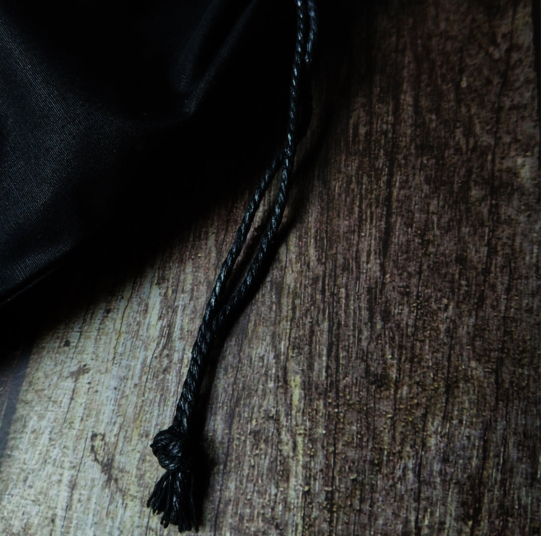 Close up of waxed cord drawstring on a textured wooden surface